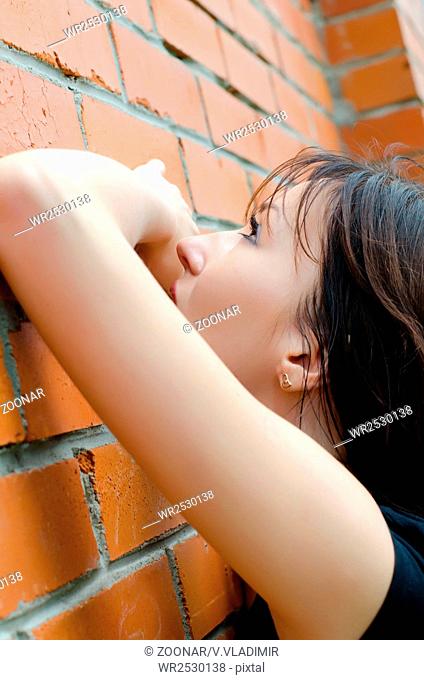 Young sad girl at brick walls