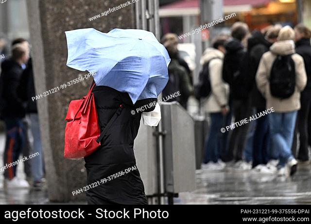 21 December 2023, North Rhine-Westphalia, Cologne: An umbrella flies around a lady's head due to a storm. Photo: Roberto Pfeil/dpa