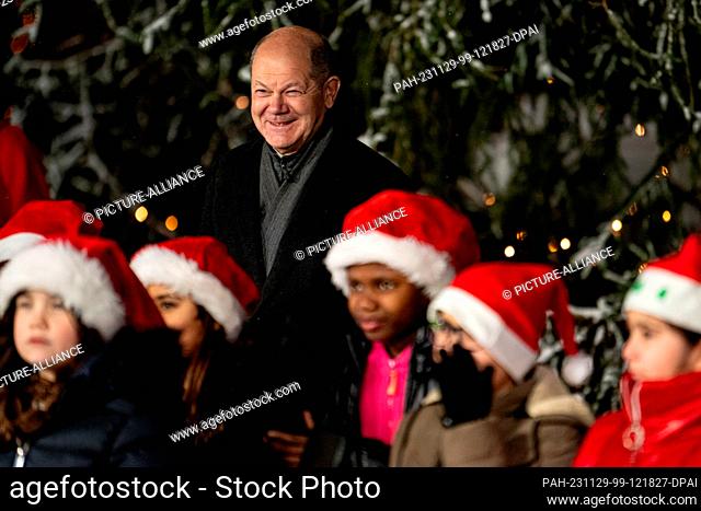 29 November 2023, Berlin: Federal Chancellor Olaf Scholz (SPD) stands behind the Christoph Földerich Primary School children's choir during the handover of the...