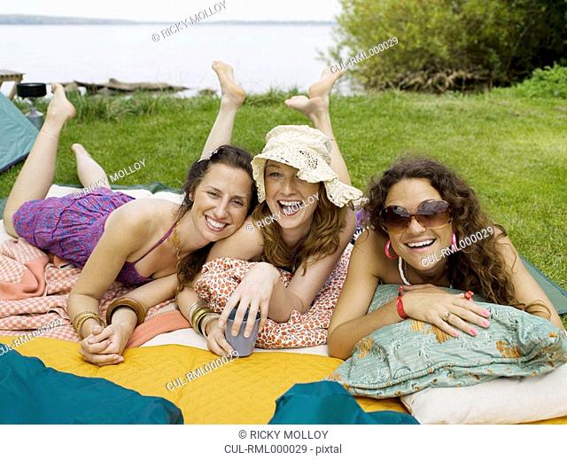 Three women laying on blankets smiling