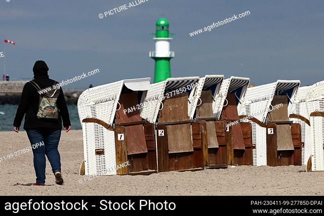 11 April 2023, Mecklenburg-Western Pomerania, Warnemünde: The first beach chairs are on the Baltic Sea beach, only a few walkers are out and about