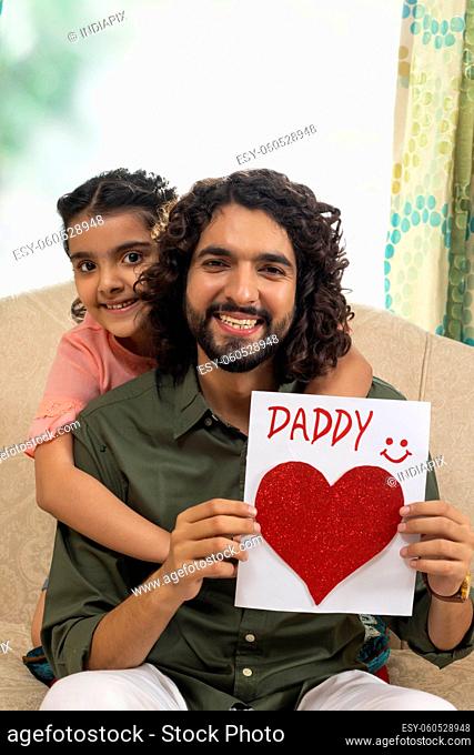 Father holding greeting card of daddy made by her daughter on Father's day