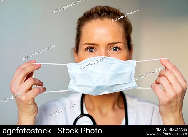 Female doctor putting protective face mask on