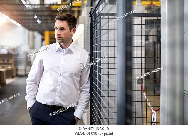 Businessman standing in factory shop floor thinking
