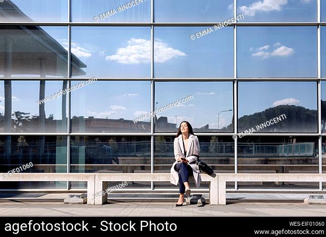 Young businesswoman sitting with eyes closed on bench