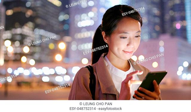 Business woman look at smart phone in city at night