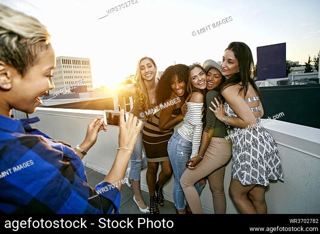A group of young women partying on a city rooftop at dusk