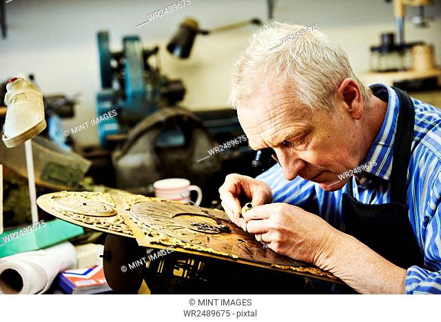 A clock maker busy in his workshop