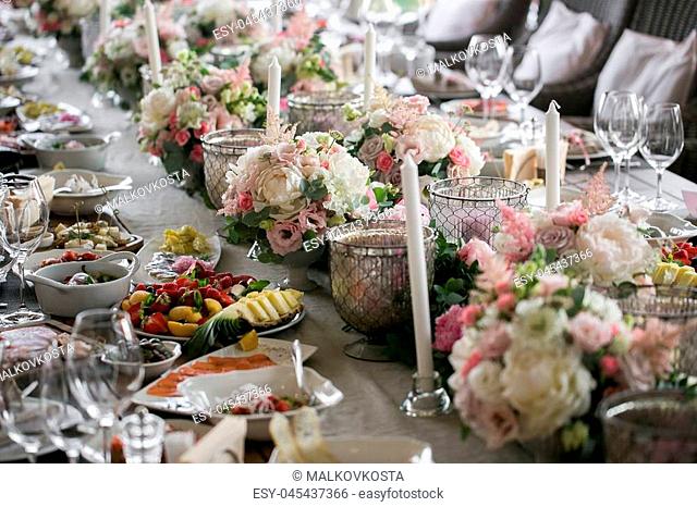 Garland of flowers and greenery for table decoration. Luxury wedding reception in restaurant. Stylish decor and adorning