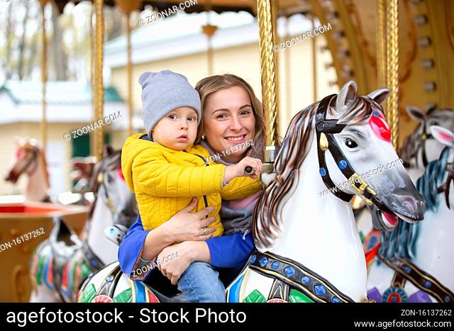 Mom with a cheerful baby on a carousel.Mother's love