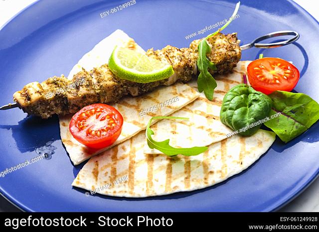herbal meat skewer with pita bread, tomatoes and lime