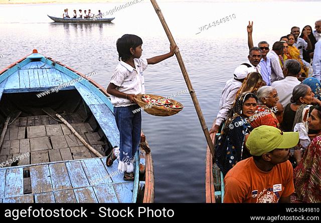 Varanasi, Uttar Pradesh, India, Asia - A girl tries to sell flowers to boat passengers at a ghat on the bank of the holy Ganges River