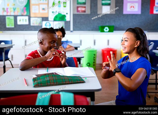African american female teacher and boy talking in hand sign language at elementary school