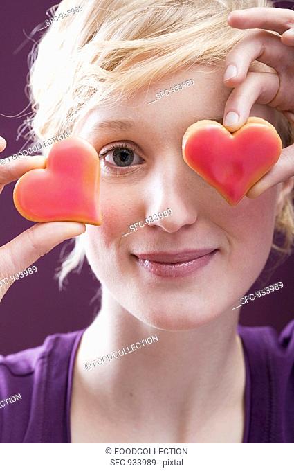 Young woman with two heart-shaped biscuits in front of her eyes