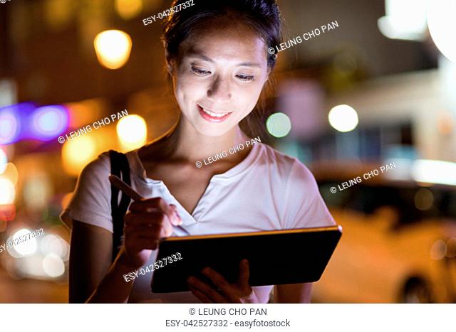 Woman use of digital tablet at night in the city