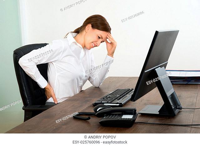 Young Businesswoman Suffering From Backache And Headache In Office