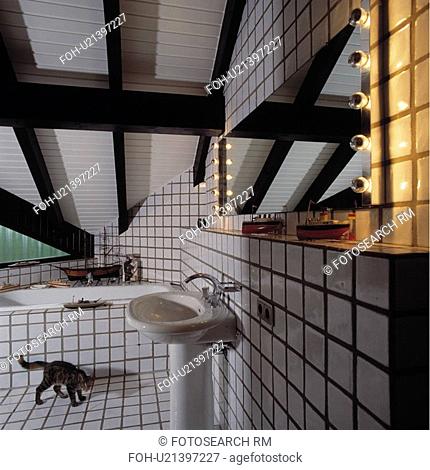 Completely white tiled modern bathroom in the attic with sloping ceiling and beams