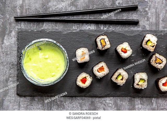 Sushi on slabe plate, wasabi in bowl, chop sticks