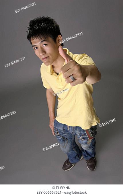 Asian young guy give you excellent sin over studio gray background