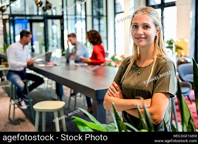 Smiling businesswoman with arms crossed at coworking office