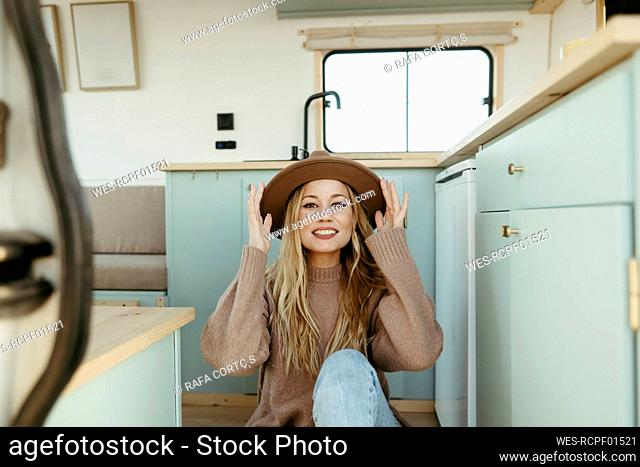 Happy young woman wearing hat sitting inside motor home