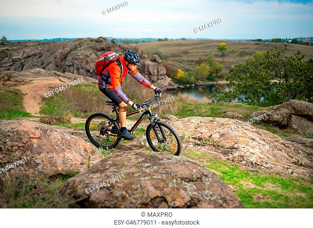 Cyclist in Red Riding the Bike on Autumn Rocky Trail. Extreme Sport and Enduro Biking Concept