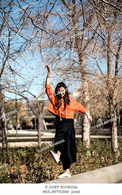 Young contemporary dancer wearing red hoodie shirt, practicing her passion in a park