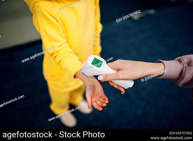 Child hand temperature measurement check by laser thermometer at kindergarten