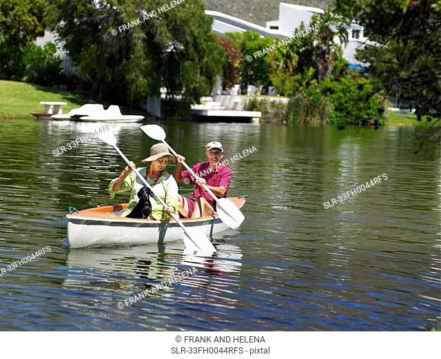 Older couple rowing canoe on lake
