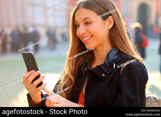 Travel concept. Beautiful young traveler woman using application map on smart phone. Tourist girl exploring city with backpack and mobile phone