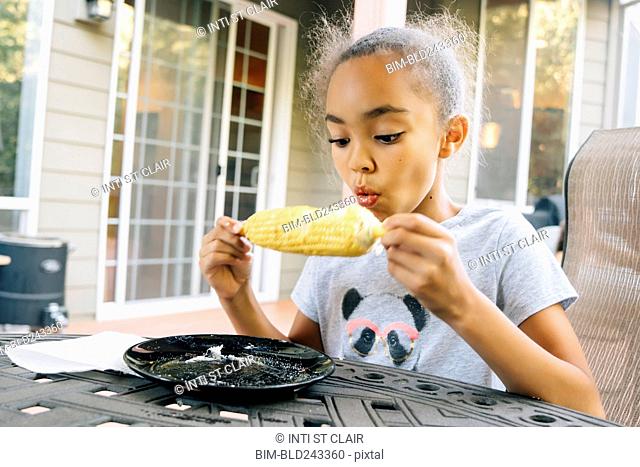 Mixed Race girl eating corn on the cob outdoors