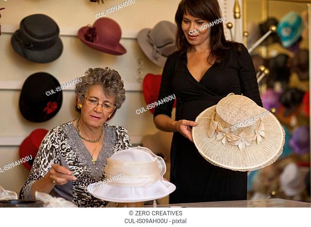 Milliner adjusting hat for customer in shop