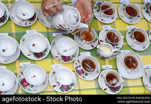 29 July 2023, Lower Saxony, Leer: Two employees of the tea museum pour tea the East Frisian way. Record attempt at the Bünting Tea Museum: serving 200 cups of...