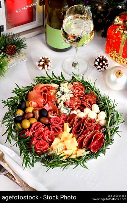 Delicacy assorted appetizer platter of salami and cheese, Parma ham, olives. An original antipasto serving for a Christmas party