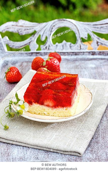 Strawberry cake with jelly topping on wooden tray in the garden