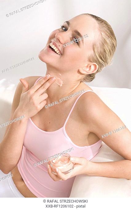 woman applying cream on neck