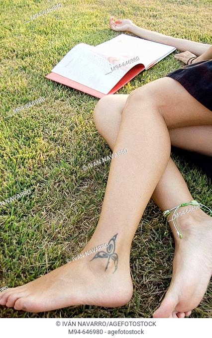 Woman laying on grass reading a book