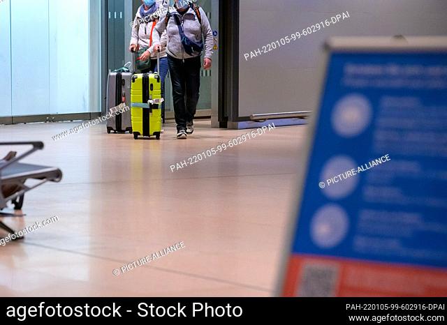04 January 2022, Hamburg: Returning passengers of the cruise ship ""Aidanova"" walk with their suitcases through the arrivals area of Hamburg airport in the...