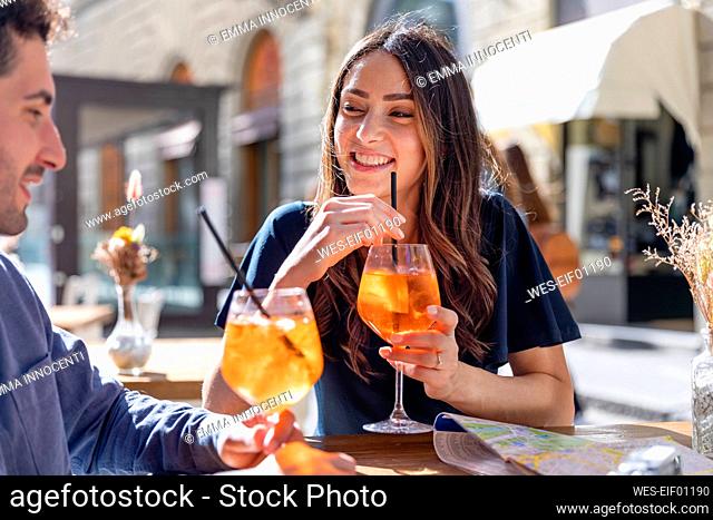 Smiling woman with drink looking at man during sunny day
