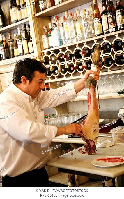 Barman cutting pieces of ham at El Rinconcillo, Sevilles oldest tapas bar, Spain