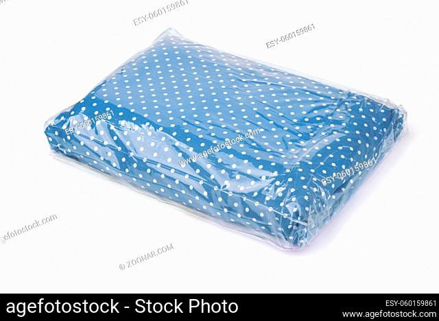 Folded bedding set in plastic storage bag isolated on white