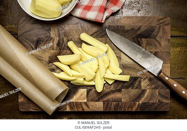 Still life of peeled and sliced potatoes, kitchen knife on chopping board