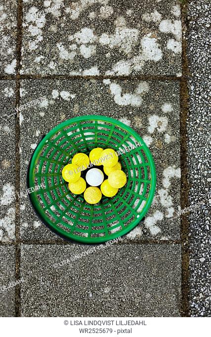 Directly above shot of golf balls in basket on paving stone