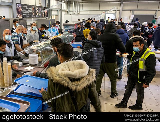 PRODUCTION - 16 November 2022, Baden-Wuerttemberg, Ellwangen: Refugees are crowding the food counter at the state's initial reception center (LEA)