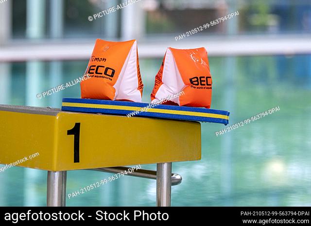 11 May 2021, Lower Saxony, Osnabrück: ILLUSTRATION - Two water wings and a swim board lie on a starting block in the Moscaubad swimming hall