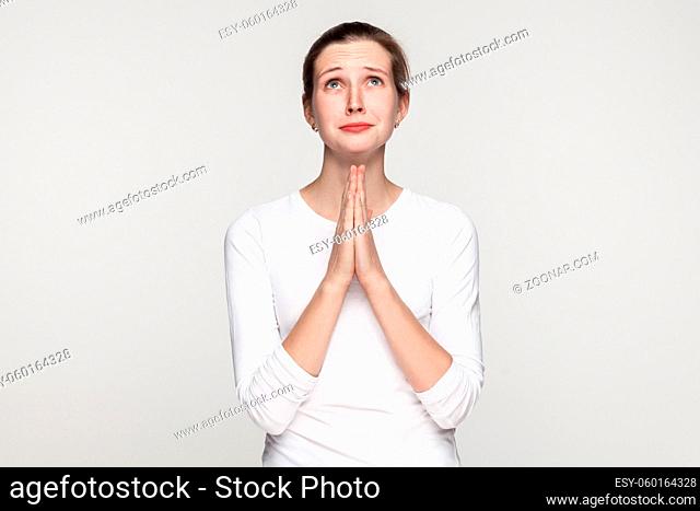 Religion concept. Prayer girl. Studio shot, isolated on gray background