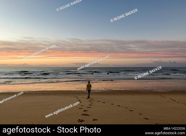 Woman runs towards the ocean surf at sunrise on the Atlantic coast