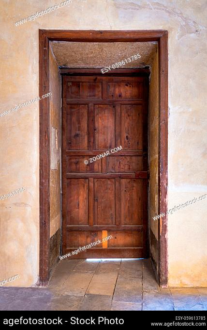 Recessed grunge wooden aged closed door on grunge stone wall, Medieval Cairo, Egypt