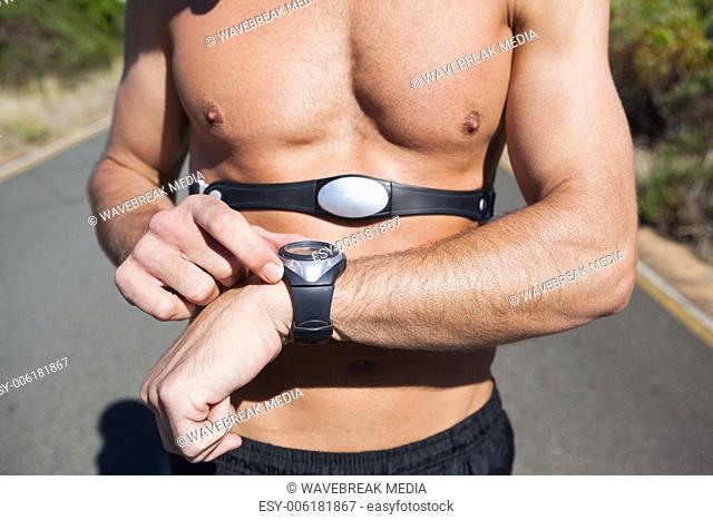 Athletic man on open road with monitor around chest