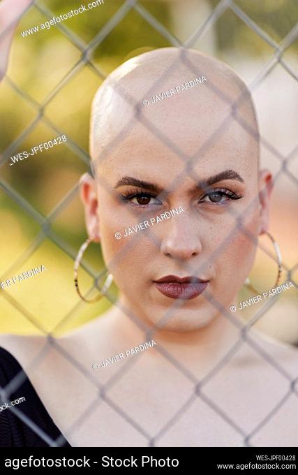 Serious transgender woman seen through chainlink fence